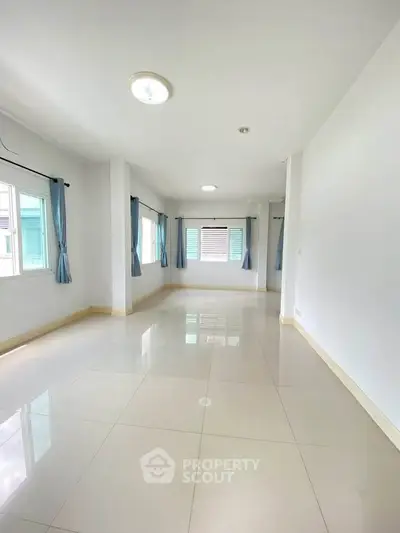 Spacious empty room with large windows and tiled flooring, perfect for customization.
