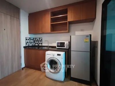Modern kitchen with appliances including washing machine and fridge in compact layout.