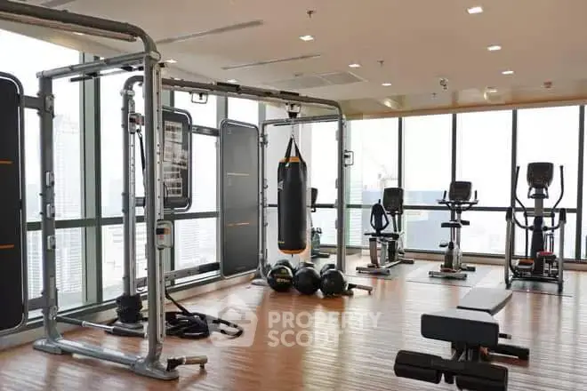 Spacious gym with modern equipment and panoramic city views in luxury apartment building.
