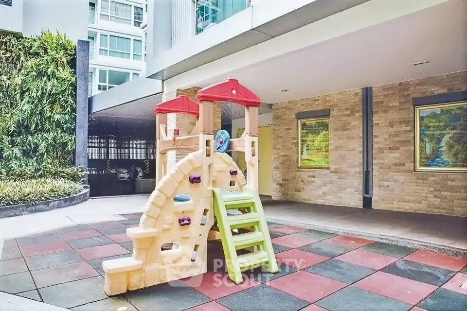 Modern residential building with children's play area and colorful playground equipment.