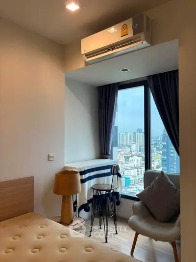 Cozy bedroom with city view, featuring modern decor and natural light.