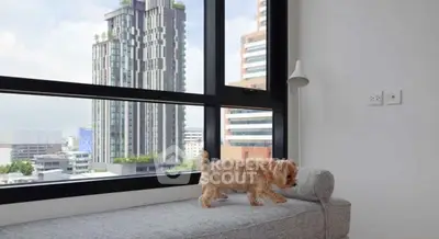 Modern apartment with large window and city view, featuring a cozy bench and stylish lamp.