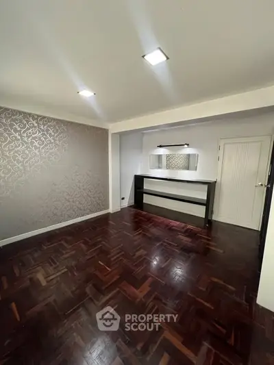 Spacious living room with elegant parquet flooring and stylish accent wall.