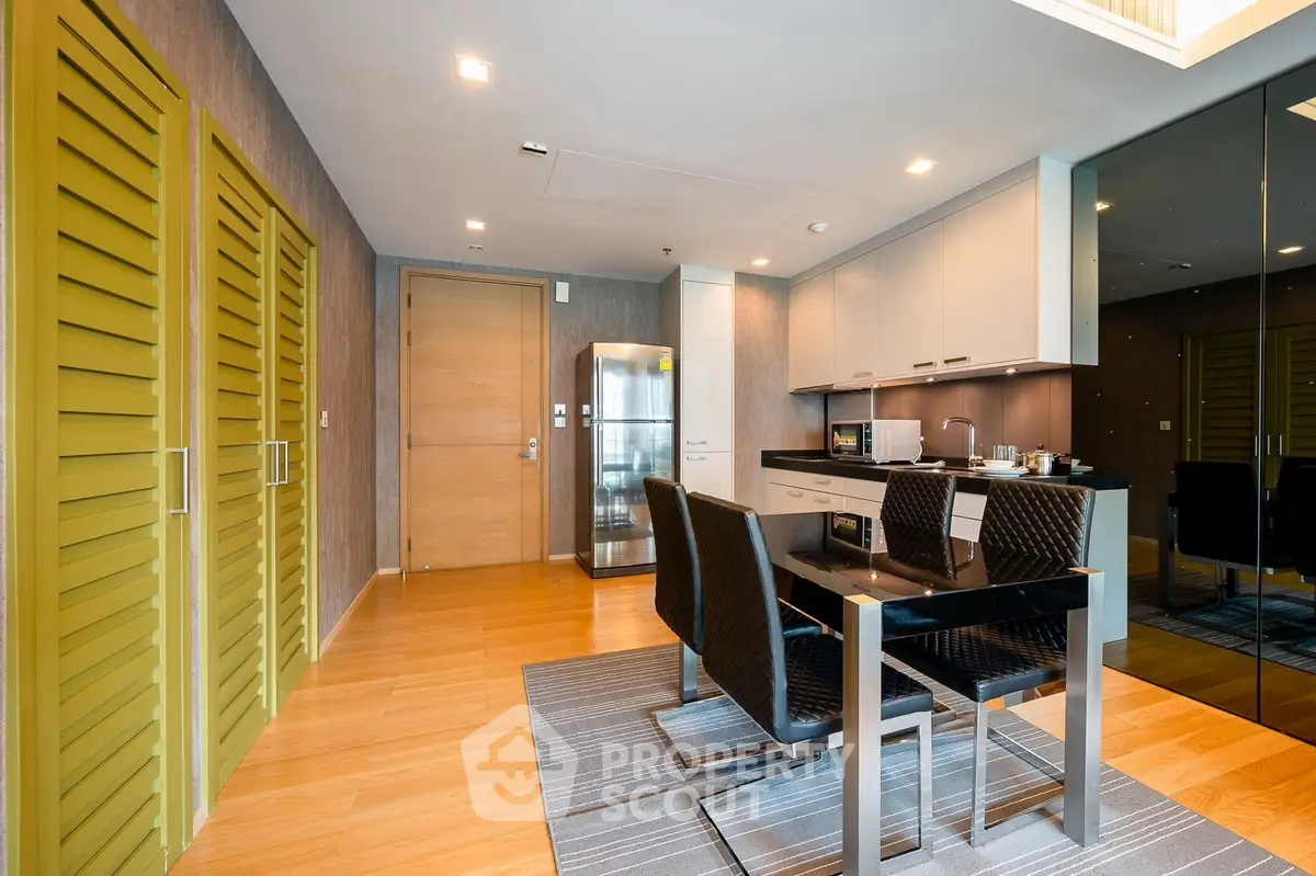 Modern kitchen with sleek design, featuring dining area and stainless steel appliances.