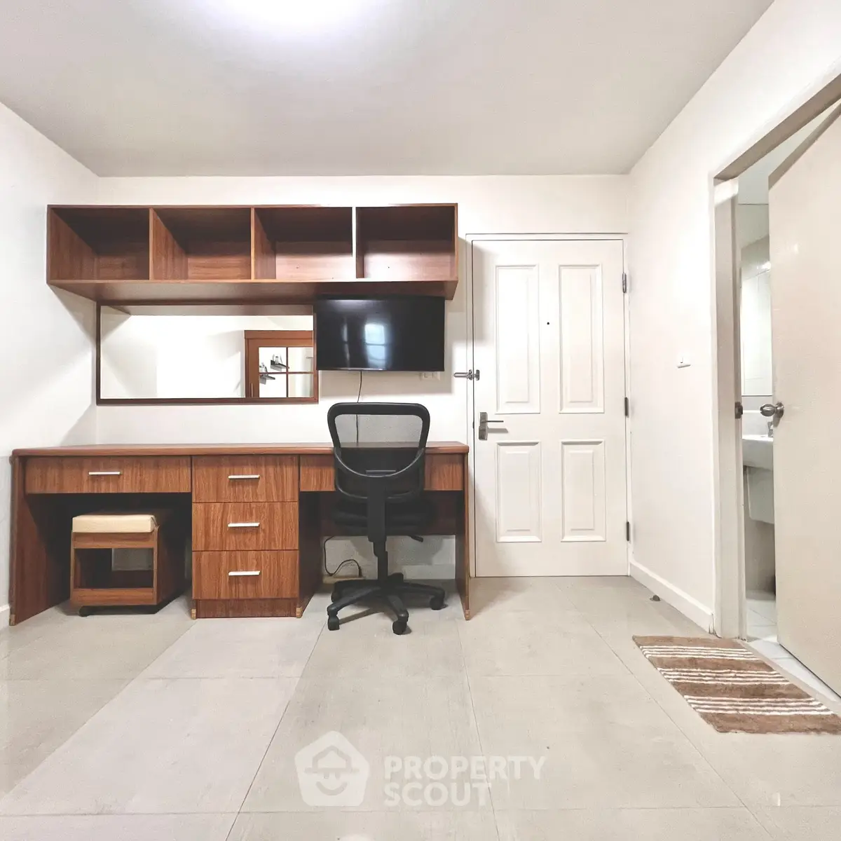 Modern study room with wooden desk, chair, and wall-mounted TV in a bright apartment.