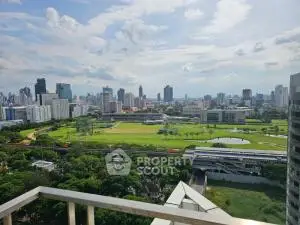 Stunning cityscape view from high-rise balcony overlooking lush green park and skyline.