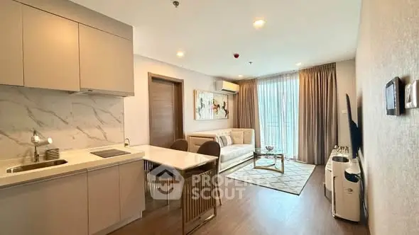 Modern open-layout living room with kitchen, featuring elegant decor and natural light.