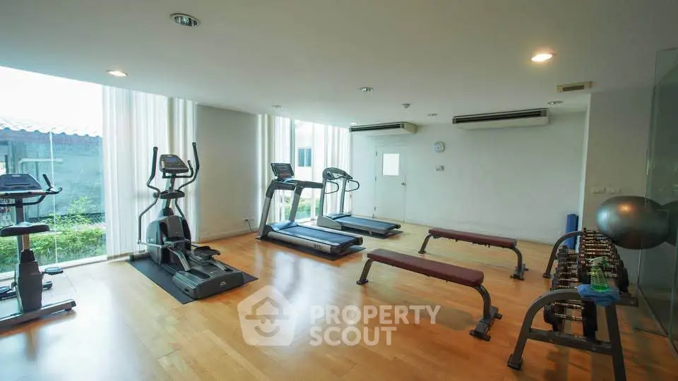 Modern gym with exercise equipment and large windows in a residential building.
