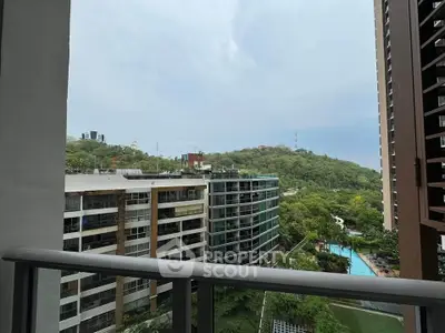 Stunning balcony view overlooking lush greenery and modern buildings with a pool.