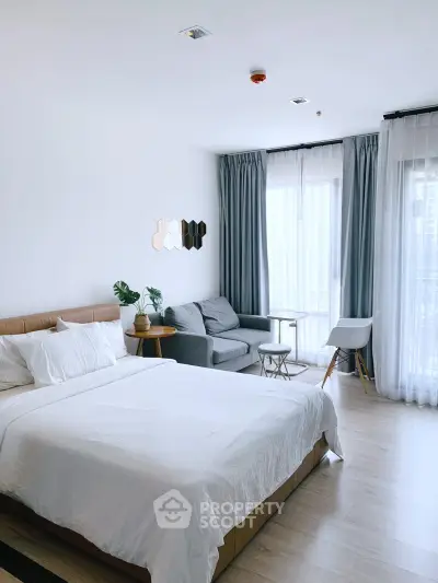 Modern bedroom with stylish decor, large windows, and cozy seating area in a bright apartment.