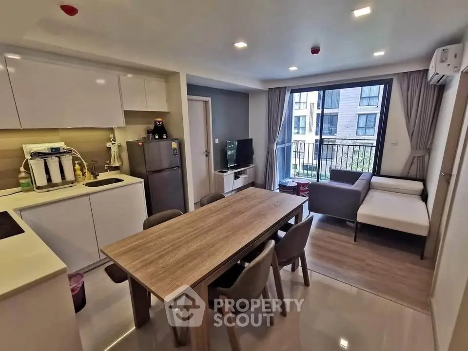 Modern open-layout kitchen and living room with balcony view in stylish apartment.