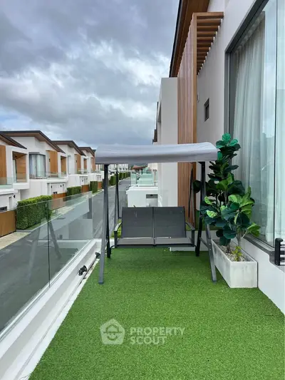Modern balcony with artificial grass and swing overlooking stylish residential street.