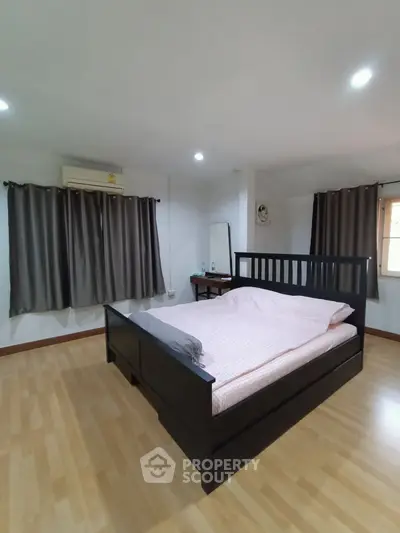 Spacious bedroom with wooden flooring and modern furnishings