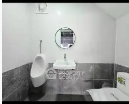 Modern bathroom with urinal, sink, and mirror in sleek design.