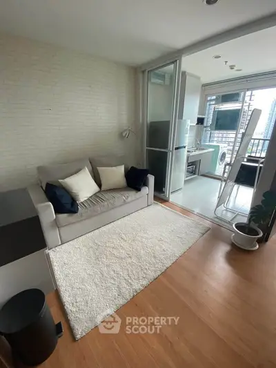 Modern living room with cozy sofa and open kitchen layout, featuring a bright balcony view.