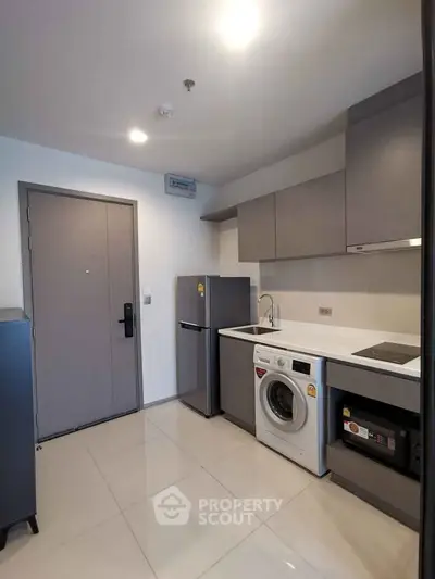 Modern kitchen with sleek appliances and minimalist design in a compact apartment unit.