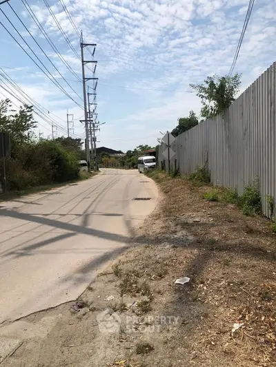 Quiet suburban street with potential for development, featuring clear skies and surrounding greenery.