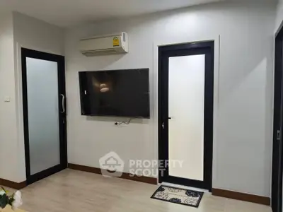 Modern living room with sleek design, featuring a wall-mounted TV and air conditioning unit.