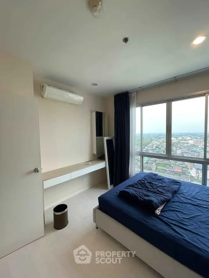 Modern bedroom with large window offering stunning city views, featuring sleek furniture and air conditioning.
