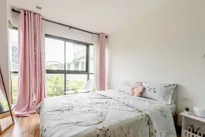 Bright and cozy bedroom with large window and pink curtains