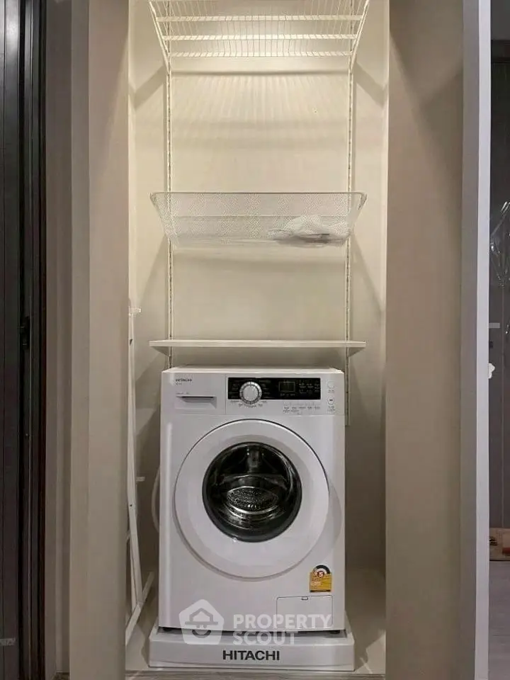 Compact laundry space with Hitachi washing machine and storage shelves.