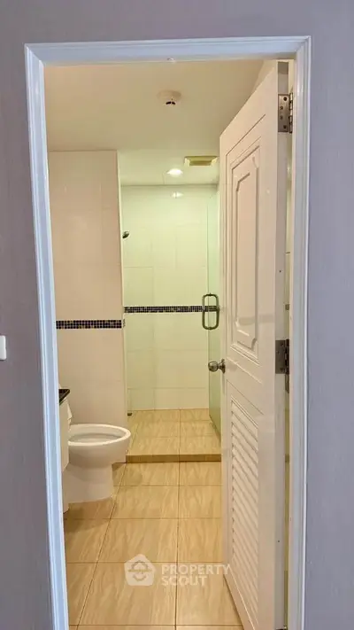 Modern bathroom with glass shower and tiled flooring in a stylish apartment.