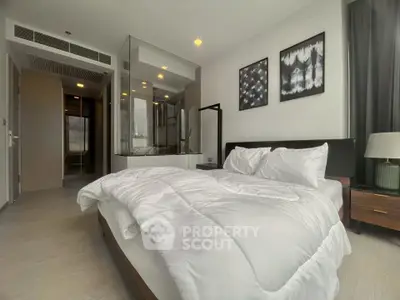 Modern bedroom with glass-enclosed bathroom and stylish decor in a luxury apartment.