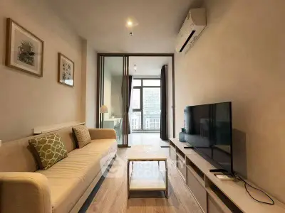 Modern living room with sleek design and city view, featuring a comfortable sofa and large TV.