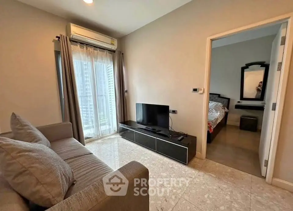 Modern living room with sleek furniture and city view, adjacent to a cozy bedroom.