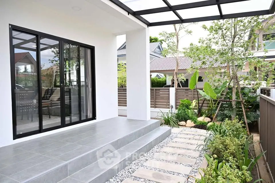 Charming modern house entrance with lush garden and sleek glass doors.