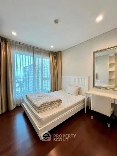 Spacious bedroom with elegant decor and large window offering city views