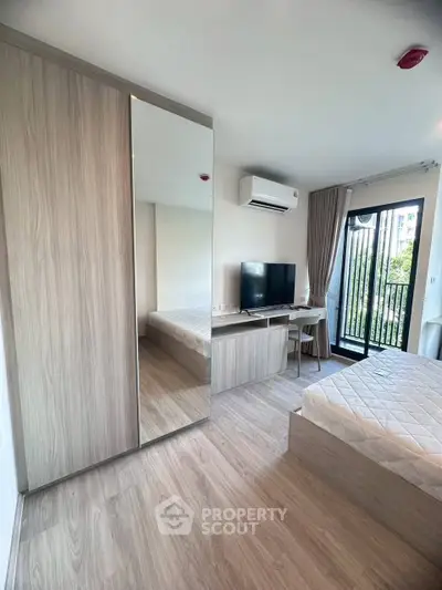 Modern bedroom with sleek design, featuring a large mirror wardrobe and balcony view.