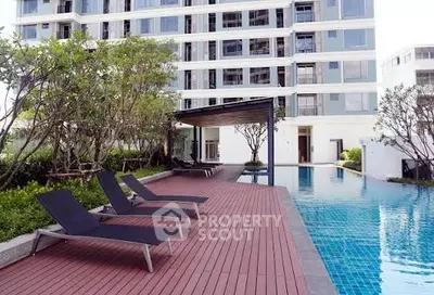Luxurious apartment building with modern poolside and lush greenery.