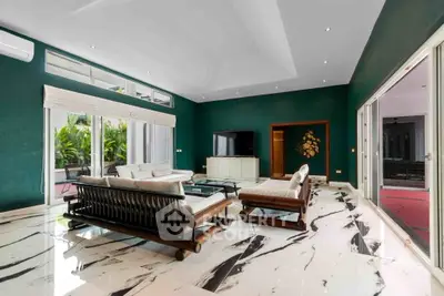 Luxurious living room with modern furniture and marble flooring, featuring large windows and a stylish green accent wall.