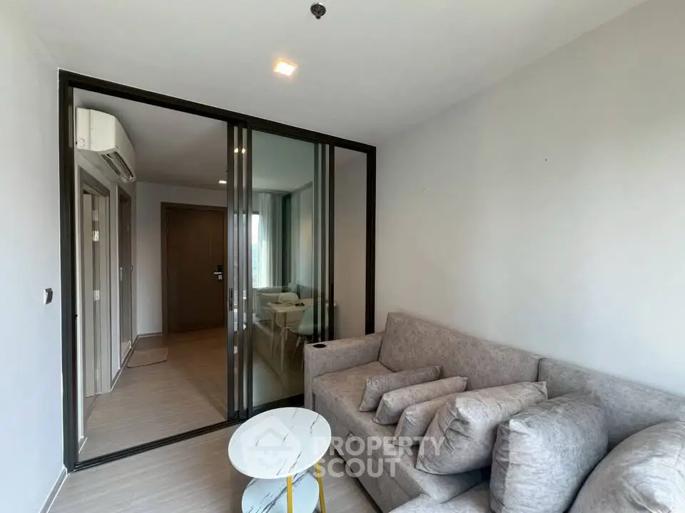 Modern living room with sliding glass doors and cozy gray sofa in a stylish apartment.