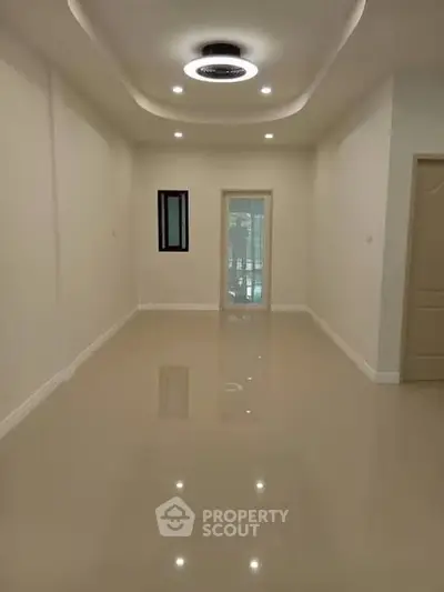 Spacious empty room with glossy floors and modern ceiling lights, perfect for customization.