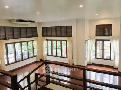 Spacious living room with large windows and wooden flooring, perfect for natural light and modern living.