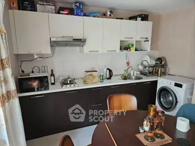 Cozy kitchen with modern appliances and dining area, featuring washing machine and microwave.