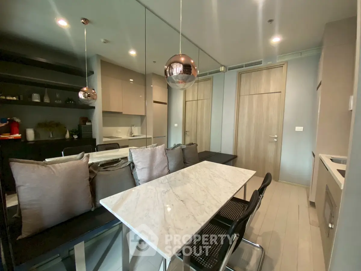 Modern dining area with marble table and stylish lighting in contemporary apartment.