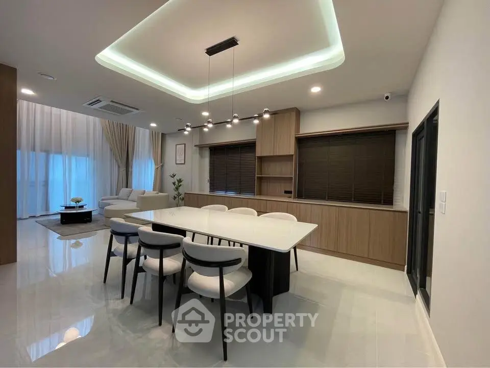 Modern open-plan living and dining area with elegant lighting and stylish furniture.