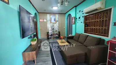 Charming living room with modern decor, large TV, and cozy seating area in vibrant turquoise setting.