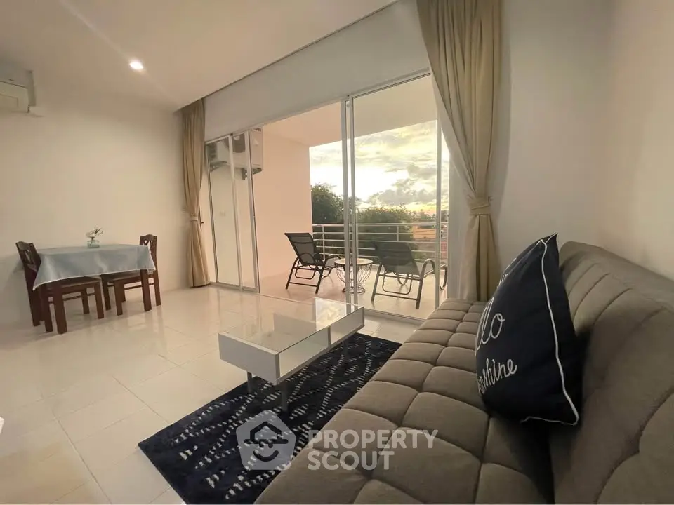 Spacious living room with balcony view, modern decor, and natural light.