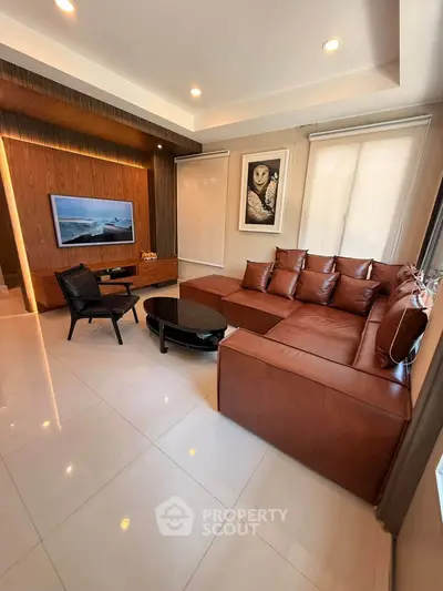 Modern living room with stylish leather sofa and wall-mounted TV in a cozy setting.