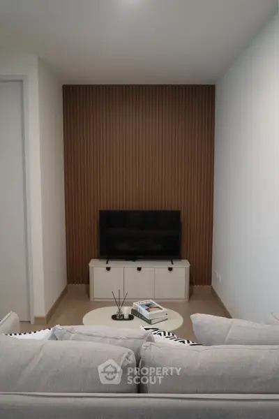 Modern living room with cozy sofa and TV setup, featuring stylish wood panel accent wall.
