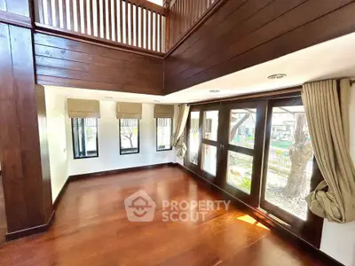 Spacious living room with wooden floors and large windows offering natural light.