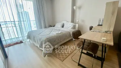 Modern bedroom with stylish decor and city view, featuring a cozy bed and functional workspace.