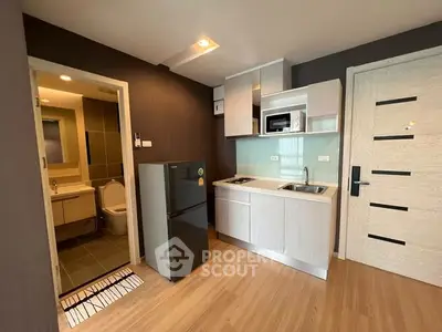Modern compact kitchen with sleek cabinetry and adjacent bathroom in a stylish apartment.