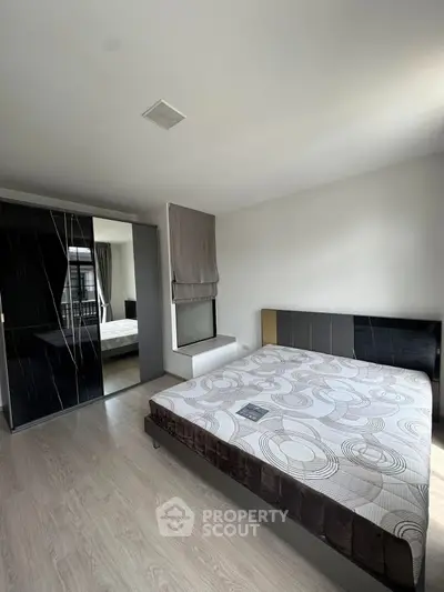 Modern bedroom with sleek design, featuring a large bed and mirrored wardrobe, perfect for urban living.