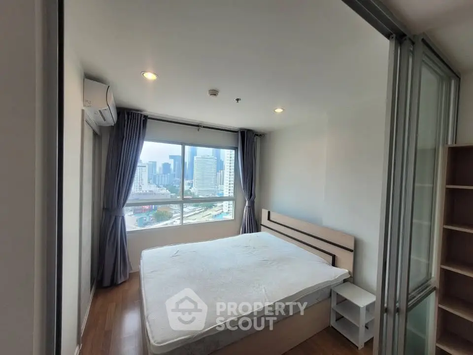 Modern bedroom with city view, featuring large windows and sleek furnishings in a high-rise apartment.