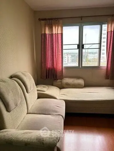 Cozy living room with large window and comfortable sofa, perfect for relaxation.